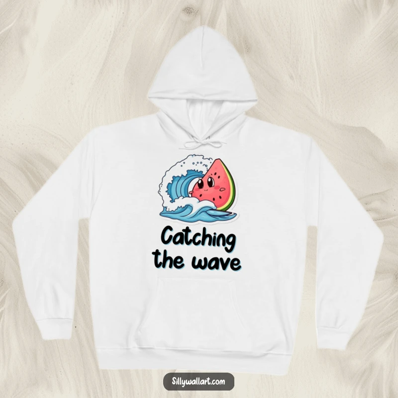 Funny watermelon with googly eyes surfing a wave, depicted on a cozy hoodie for warm and humorous beachwear.